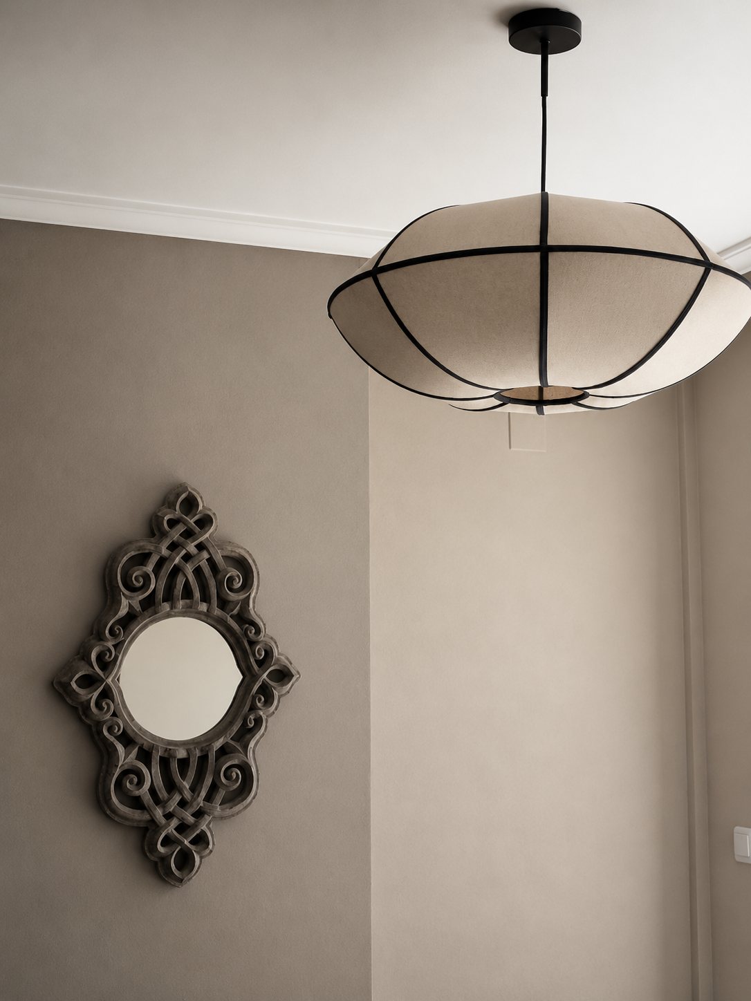 Sculptural fabric pendant hanging above a carved mirror in the Casa del Mar living room