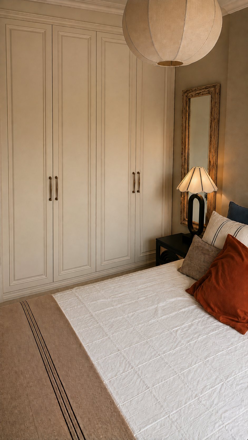 Guest bedroom with panelled fitted wardrobes, a paper pendant and a tall timber mirror