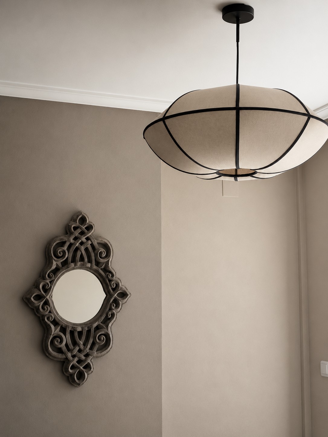 A carefully styled interior detail with a sculptural pendant and decorative mirror