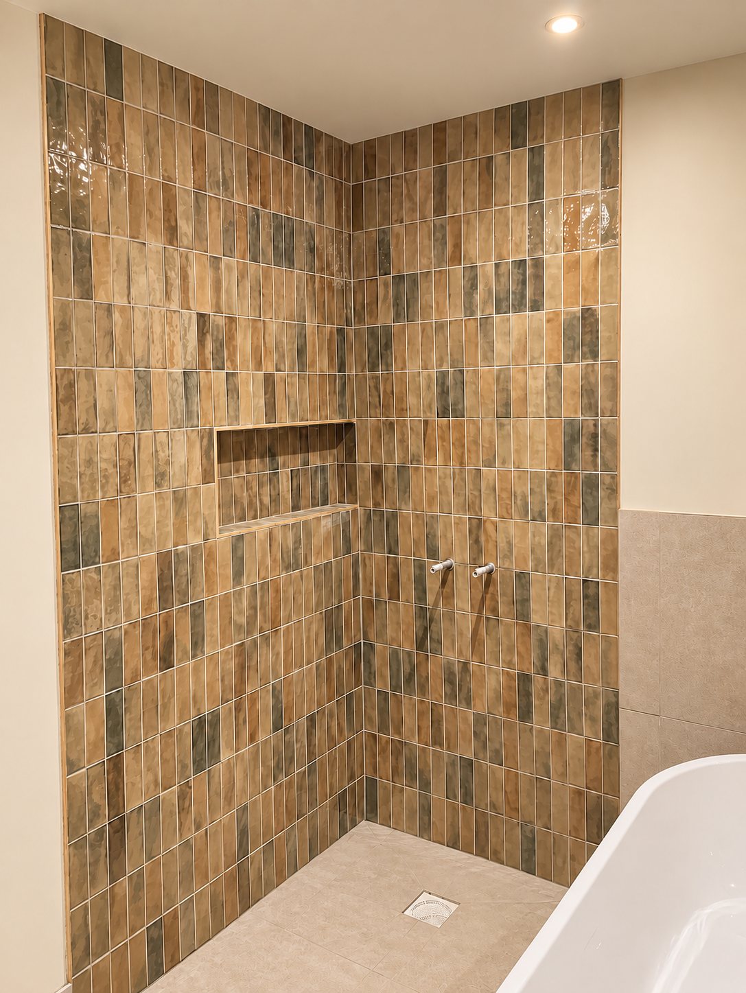 Warm tiled bathroom wall with a recessed shelf