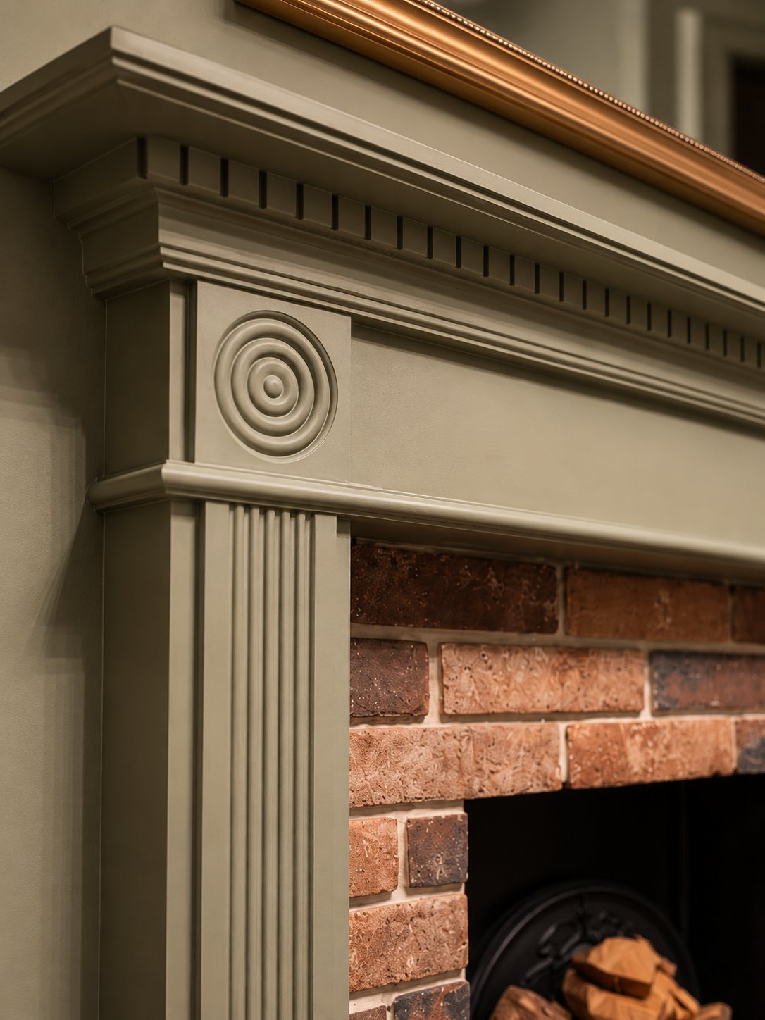 Treron green fire surround with a carved roundel and brick slips