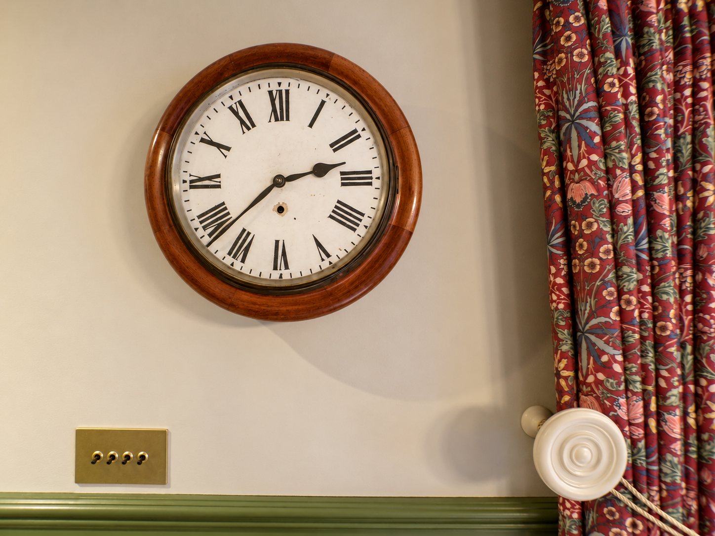 Round heritage wall clock in a timber case above sap green panelling