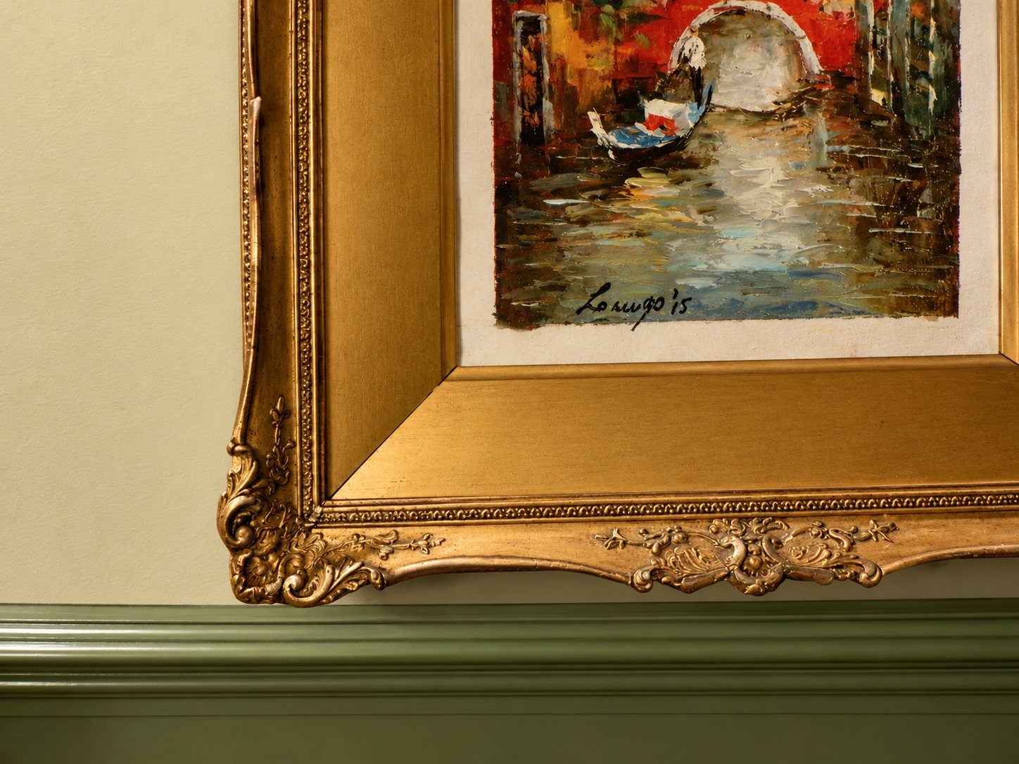 Ornate gilded frame around a canal painting above green panelling