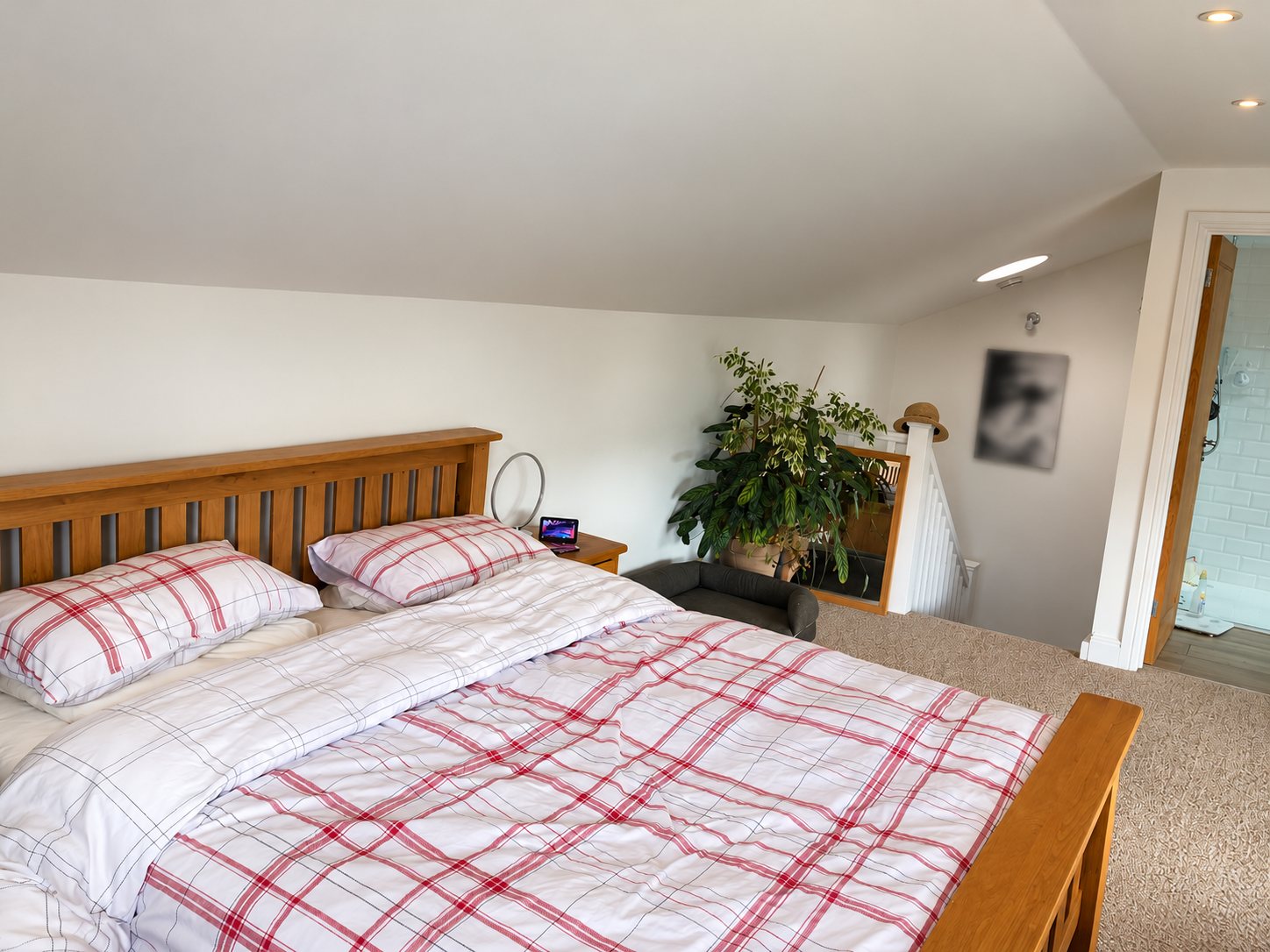 The bedroom at the top of the stairs before, with white walls and a timber bed