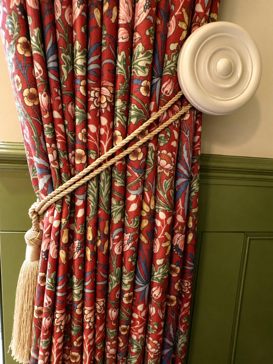 William Morris patterned curtain held back by a cord tie and ceiling-rose holdback