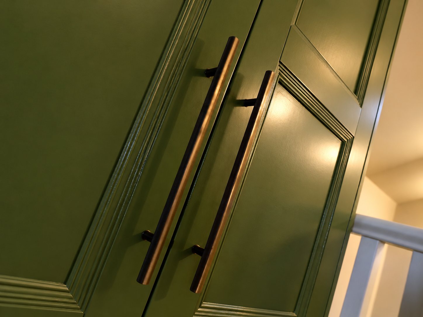 Brass bar handles on the green bedroom wardrobe doors