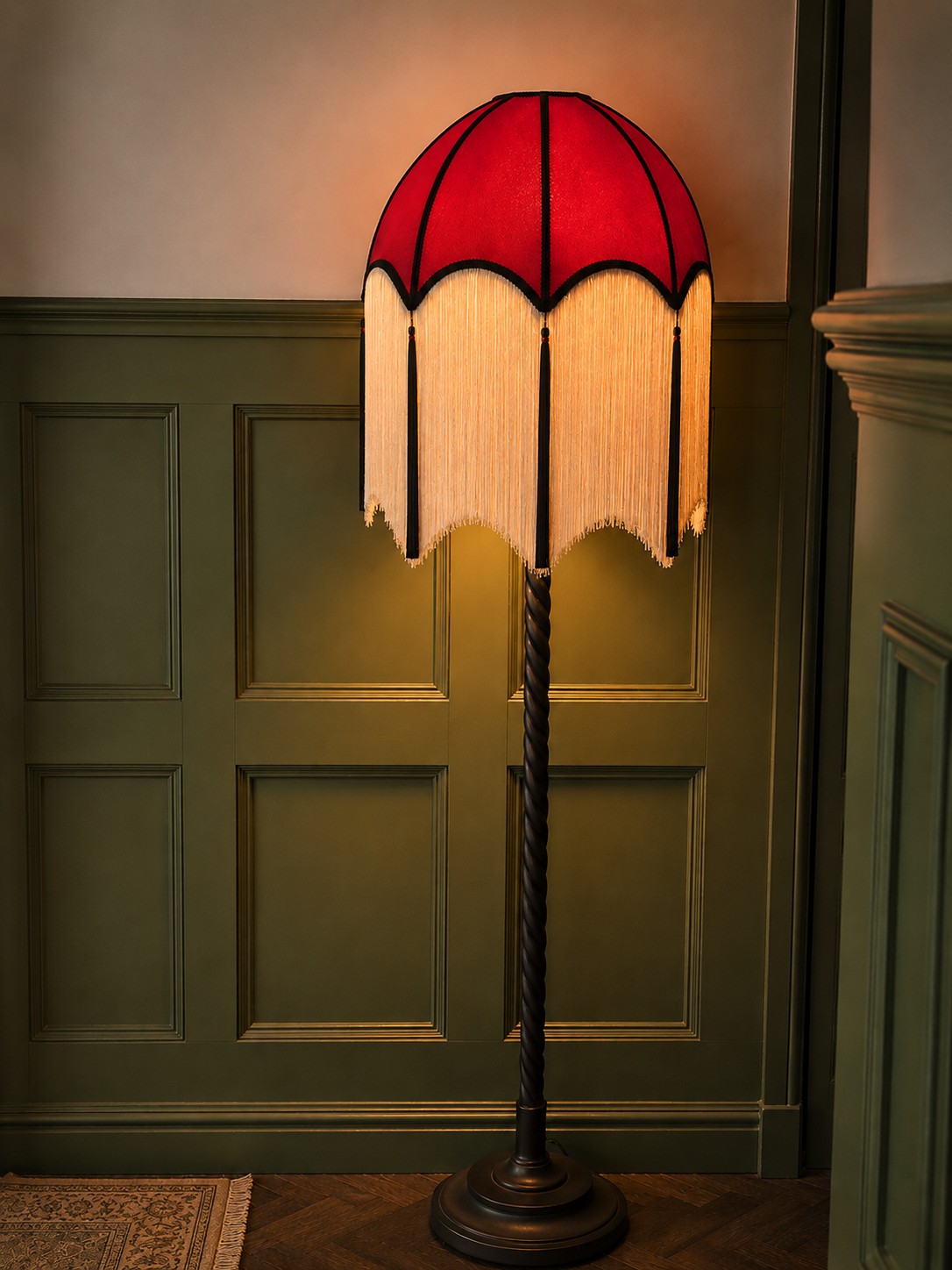 A glowing red fringed floor lamp against deep green wall panelling